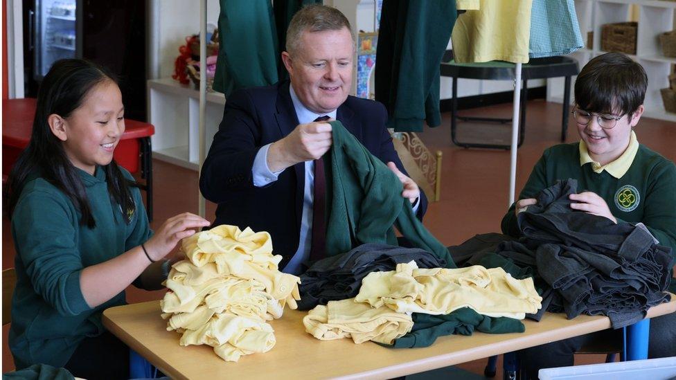 Education Minister Jeremy Miles with pupils and a pile of school uniforms