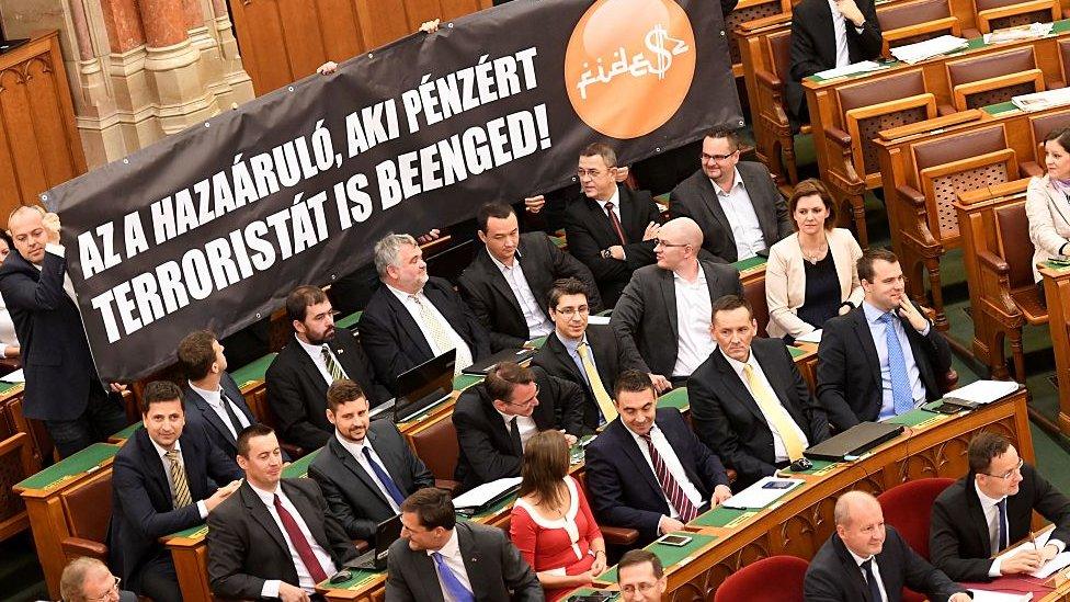 Representatives of Hungary's radical right Jobbik party hold a banner reading: "The traitor is the one who allows terrorists into the country for money" during a session at parliament on 8 November 2016 in Budapest, after a parliamentary vote on a constitutional amendment to ban the mass relocation of migrants.