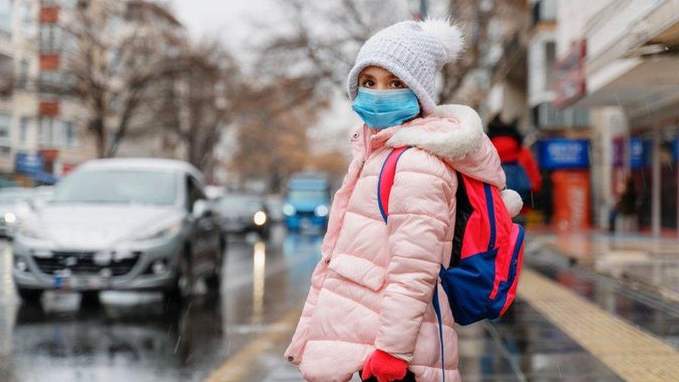 Girl in mask, next to road