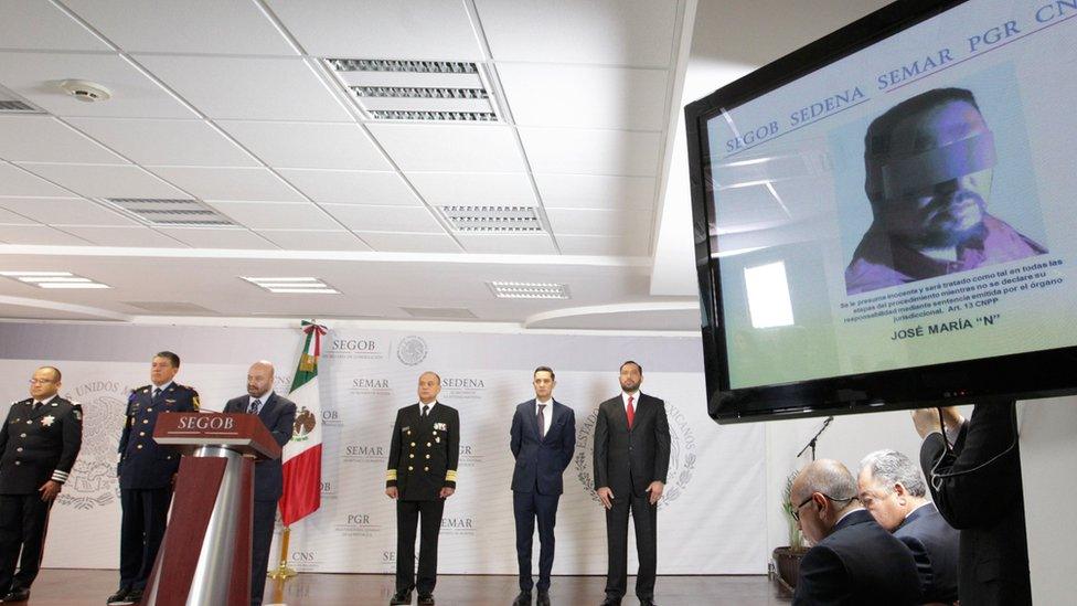 A screen shows a picture of cartel leader Jose Maria Guizar Valencia (R) during a press conference in Mexico City, 9 February 2018