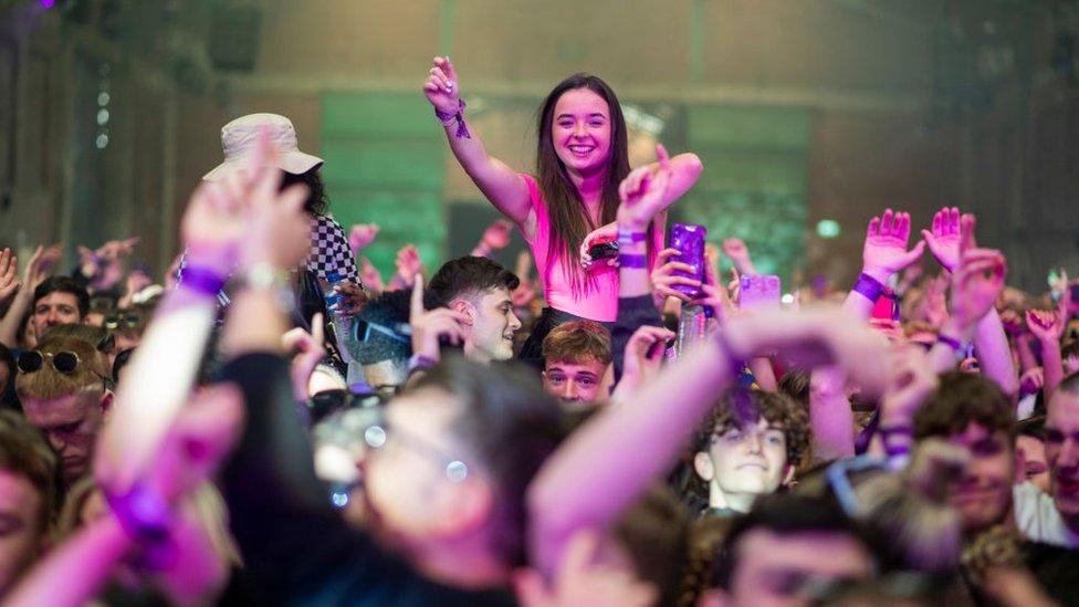 A woman dances on someone's shoulders at the club night