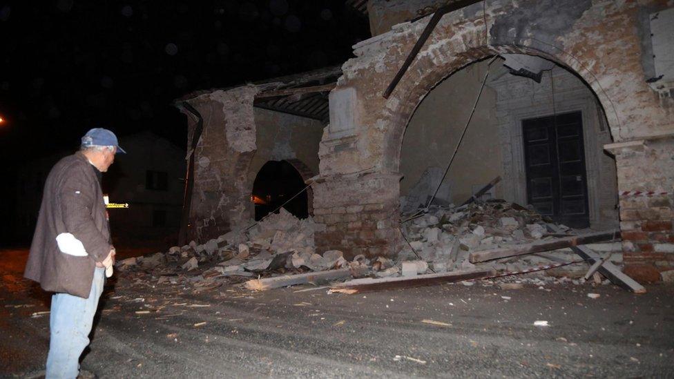 People walk past rubble in Villa Sant'Antonio village, near Visso, Marche region, Italy, on 26 October 2016