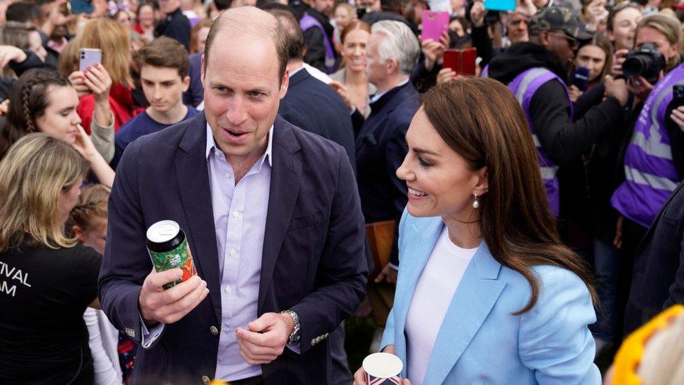 Prince William, Prince of Wales holds a can of 'Return of the King' Coronation Ale as he stands next to Catherine, Princess of Wales as they speak to people during a walkabout meeting members of the public on the Long Walk near Windsor Castle,