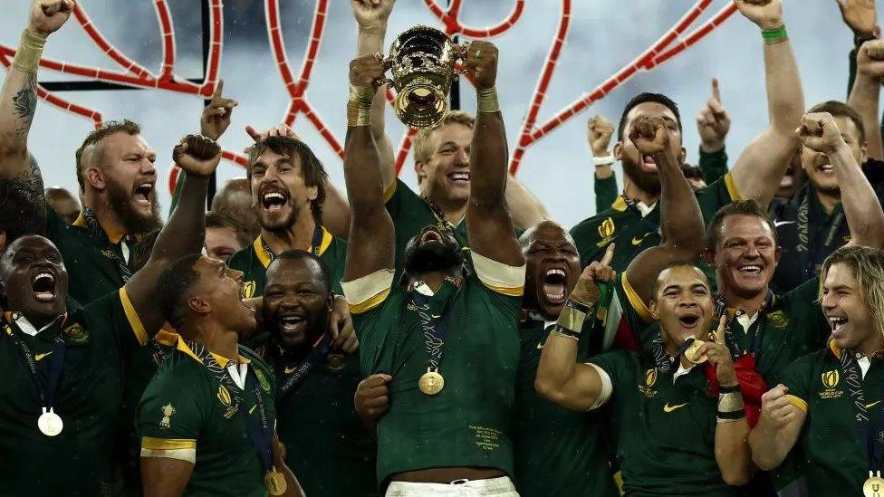 The rugby team cheering holding the trophy