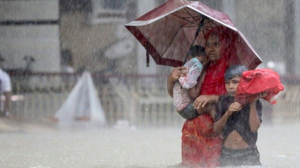 People wade through the water as they look for shelter during a flood, amidst heavy rains that caused widespread flooding in the northeastern part of the country, in Sylhet, Bangladesh, June 18, 2022.