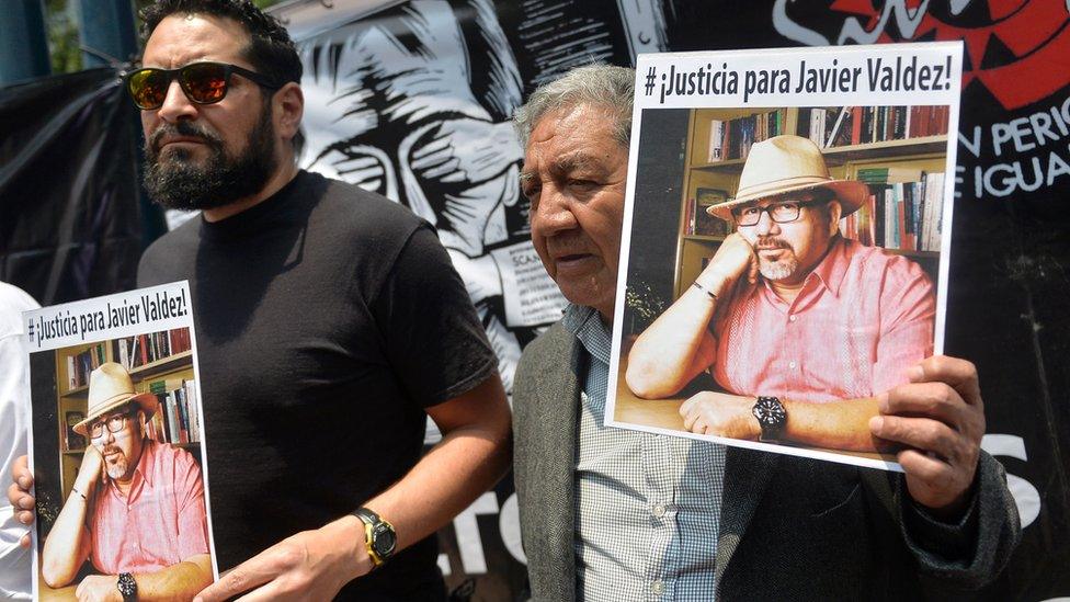 Two men holding up pictures of Javier Valdez