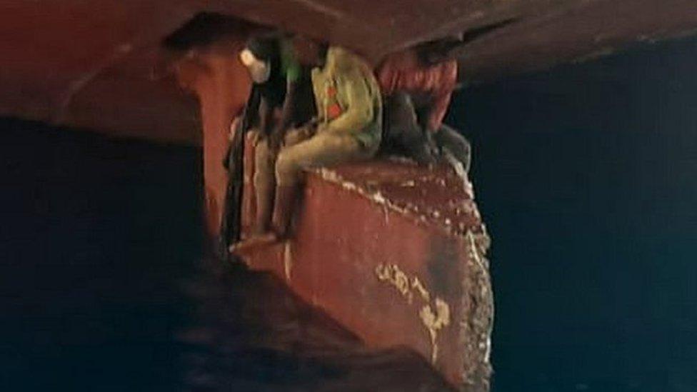 Three people sitting on a ship's rudder