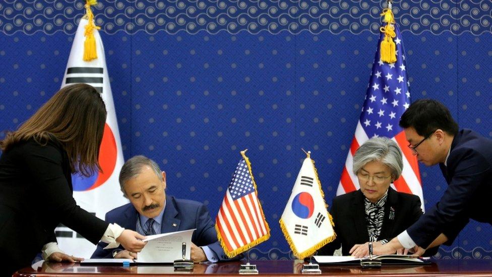 South Korean Foreign Minister Kang Kyung-wha and US ambassador to South Korea Harry Harris, sign documents at the Foreign Ministry in Seoul