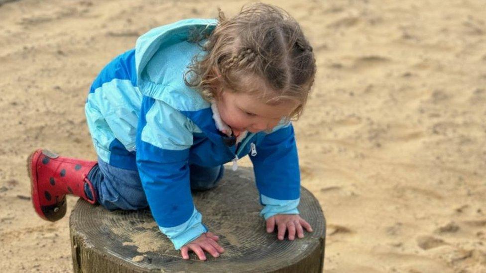 Esmee playing in a park in a blue coat