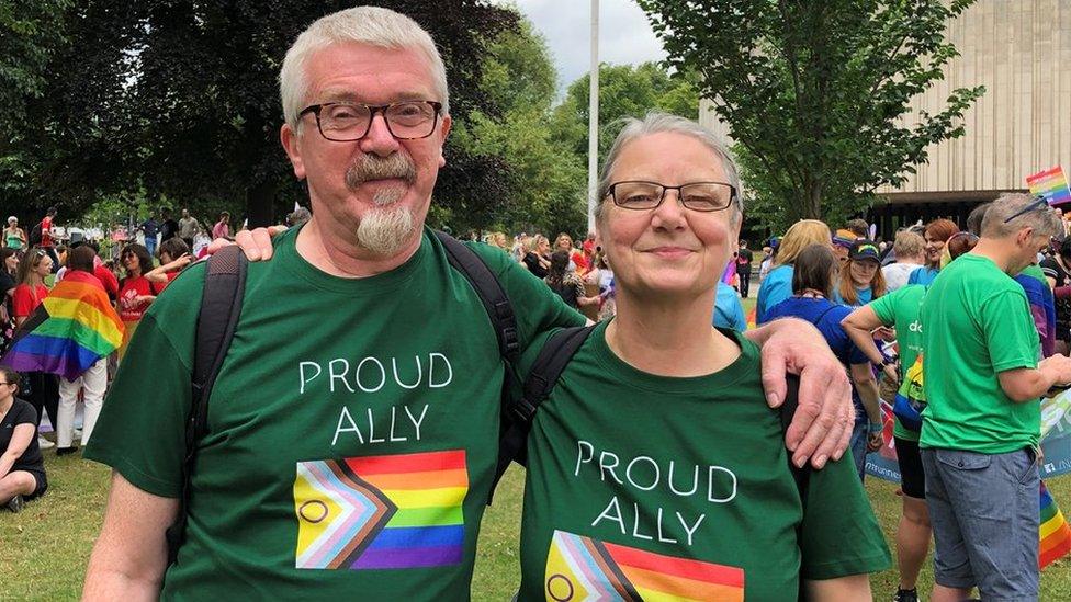 A couple wearing Proud Ally t-shirts smile at the camera