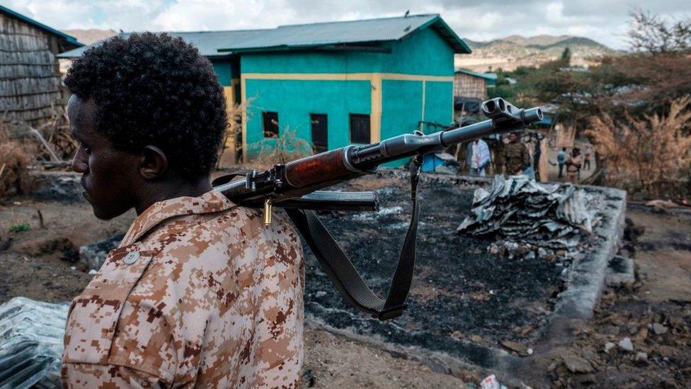 A member of the Afar Special Forces holds a gun next to a damaged house in the village of Bisober in Ethiopia's Tigray region, on December 9, 2020