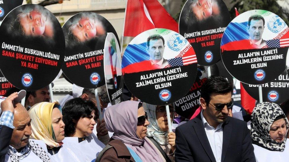 People holds placards during a protest against Russia for its alleged role in a chemical attack in the Syrian province of Idlib, on April 7, 2017 in front of the Russian embassy, in Ankara