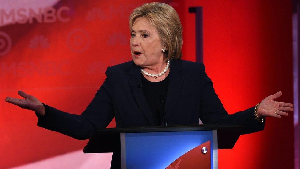 Hillary Clinton mid-sentence, shrugging, at a lecturn