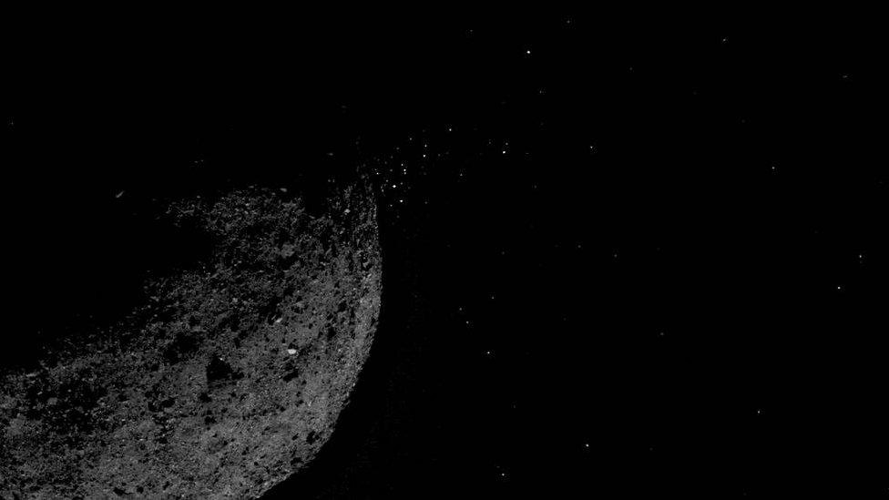 View of asteroid Bennu releasing particles from its surface