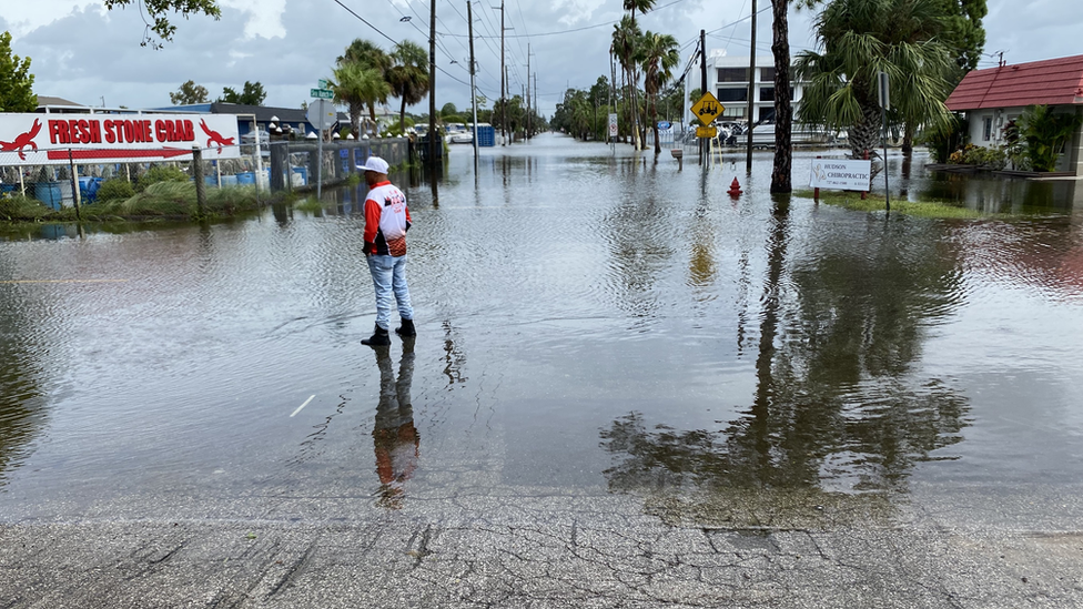 Photo of a man standing in the middle of a flooded street in Hudson