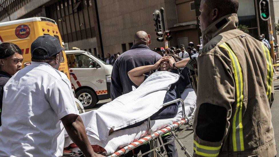 A woman receives medical attention after being evacuated from a building on fire in Johannesburg, South Africa - 5 September 2018