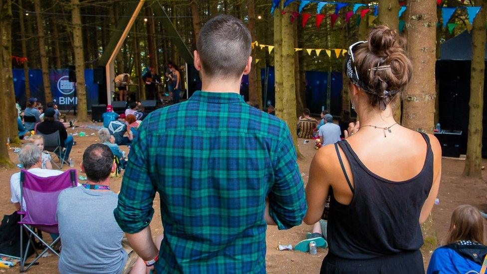 Two friends stand together at a festival