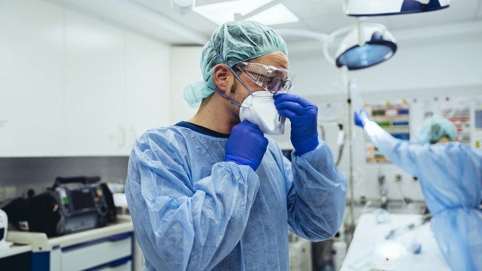 Doctor putting on FFP2 mask in emergency room of a hospital