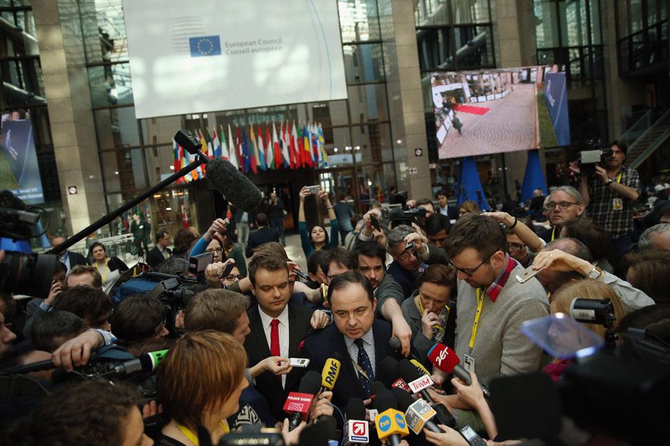 Journalists scramble to speak to a Polish minister at the European summit