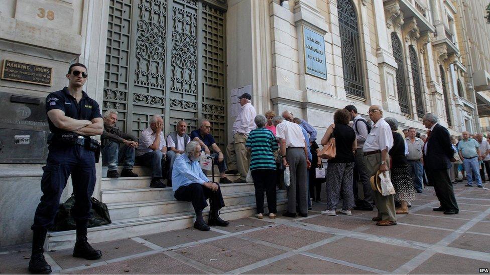 A policeman stands guard as Greek pensioners line up to get part of their pensions in front of a branch of National Bank of Greece in Athens, Greece (9 July 2015)