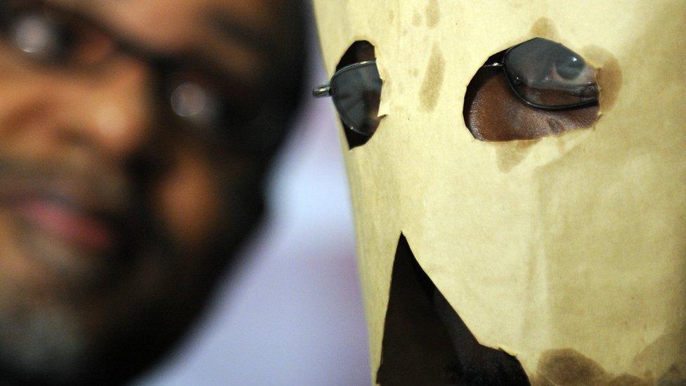 Moses (R), a gay Ugandan man seeking asylum in the United States, hides his face with a makeshift hood as he attends a press conference in Washington, DC - 2010