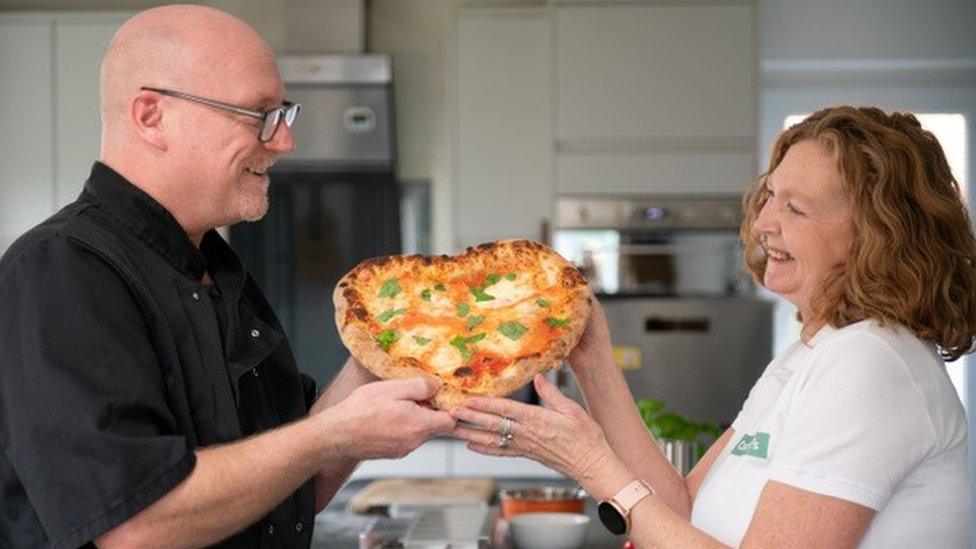 Ms Willoughby and Eliot holding a heart shaped pizza