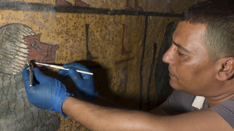 A conservationist uses specialist tools to restore a wall painting