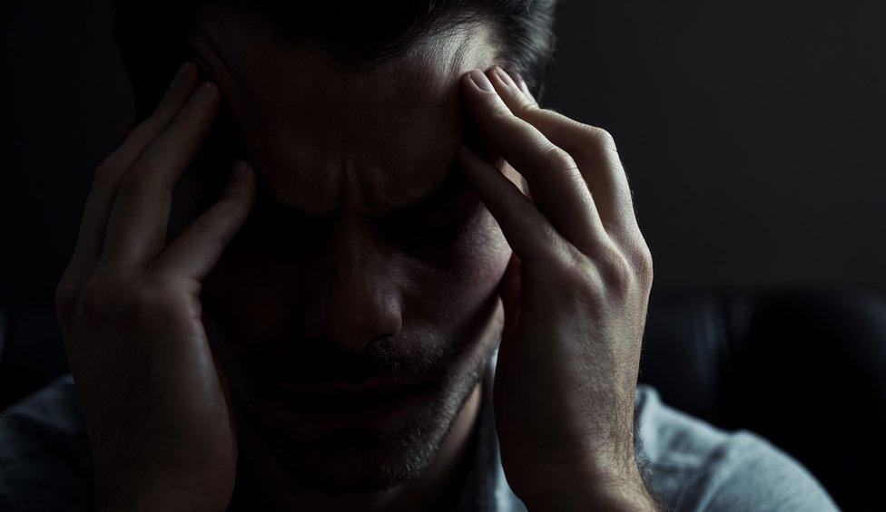 A man with his head in his hands (posed by model)