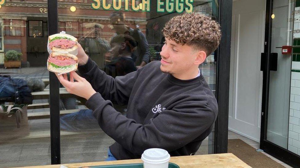 A young man holding up a sandwich