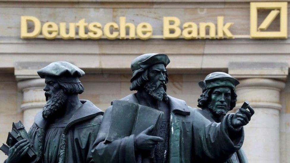 Statues in front of Deutsche Bank sign