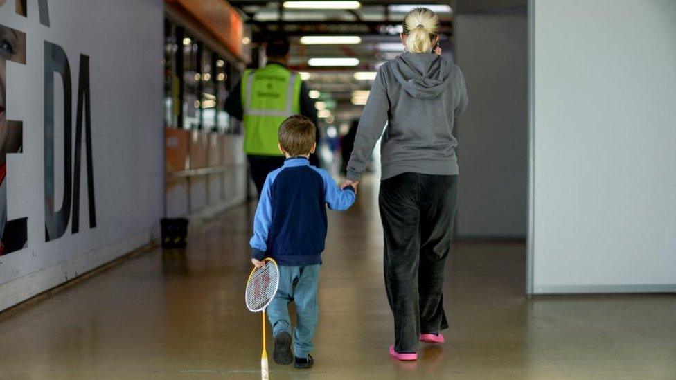 A refugee with a child walks at an accommodation centre for refugees, including Ukrainians, inside former airport Tegel in Berlin, Germany November 9, 2022