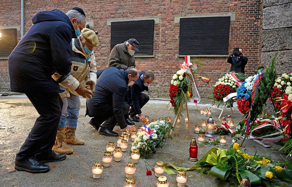 Mr Castex joins survivors and event participants in placing candles at the "death wall", where Nazi SS soldiers shot and killed several thousand victims in Auschwitz-Birkenau concentration camp on 27 January 2022