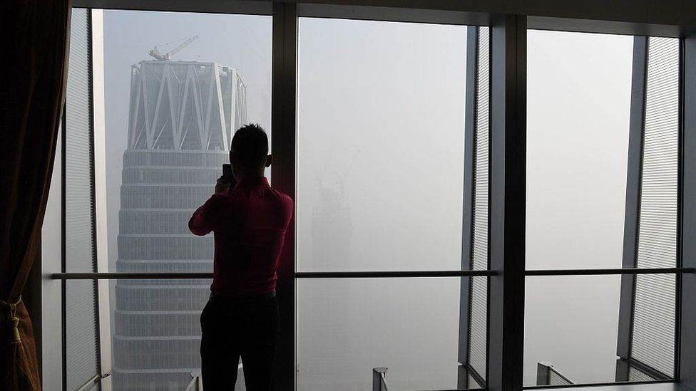 A man takes photos of buildings on a polluted day in Beijing