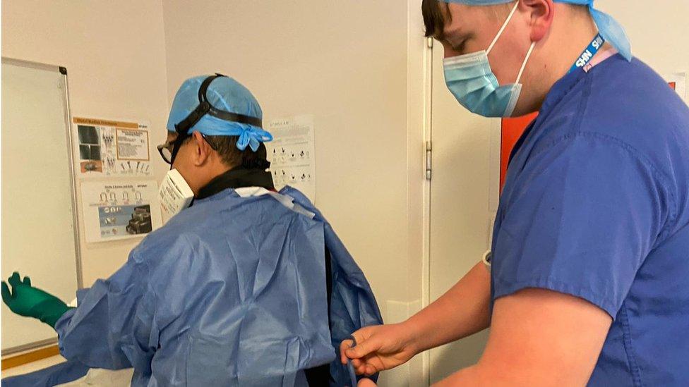 Ryan Davies tying PPE onto a colleague