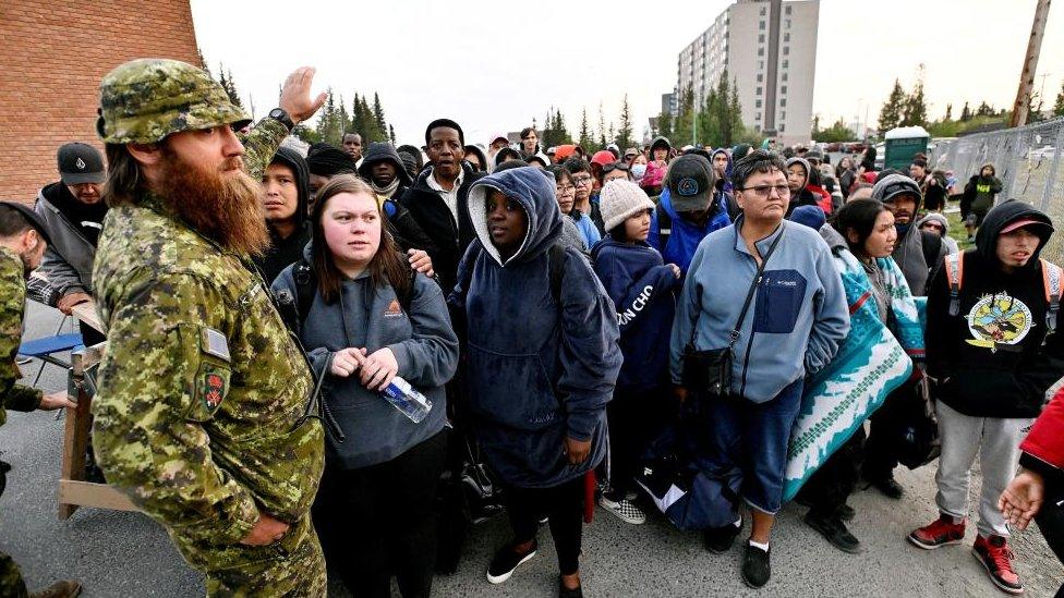 People line up outside of a local school to register to be evacuated, as wildfires threatened the Northwest Territories town of Yellowknife, Canada, August 17, 2023. REUTERS/Jennifer Gauthier TPX IMAGES OF THE DAY