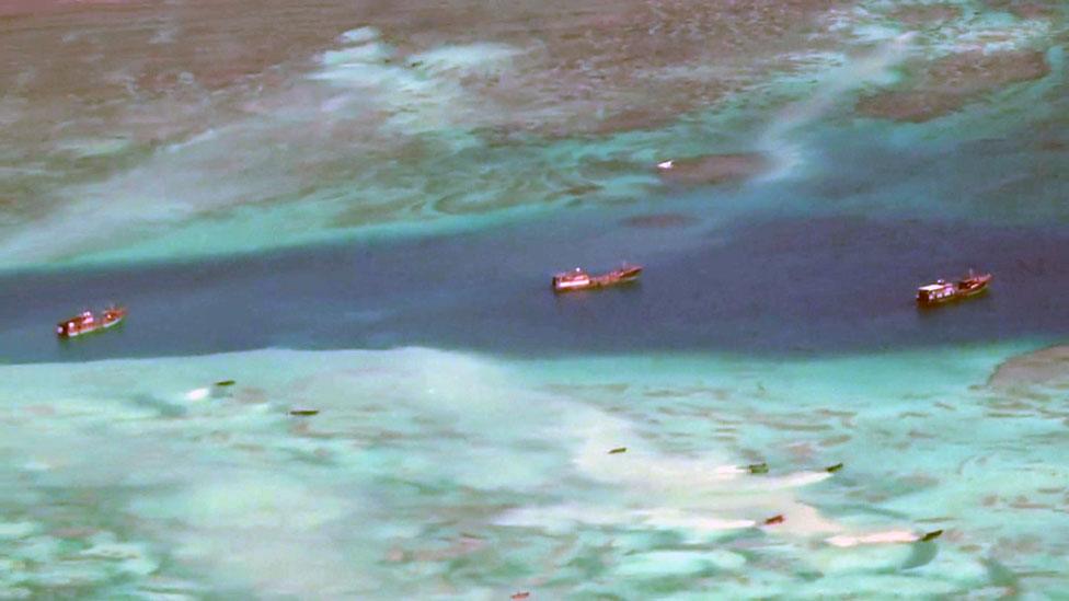 Pale plumes stretch out behind the small boats in the foreground