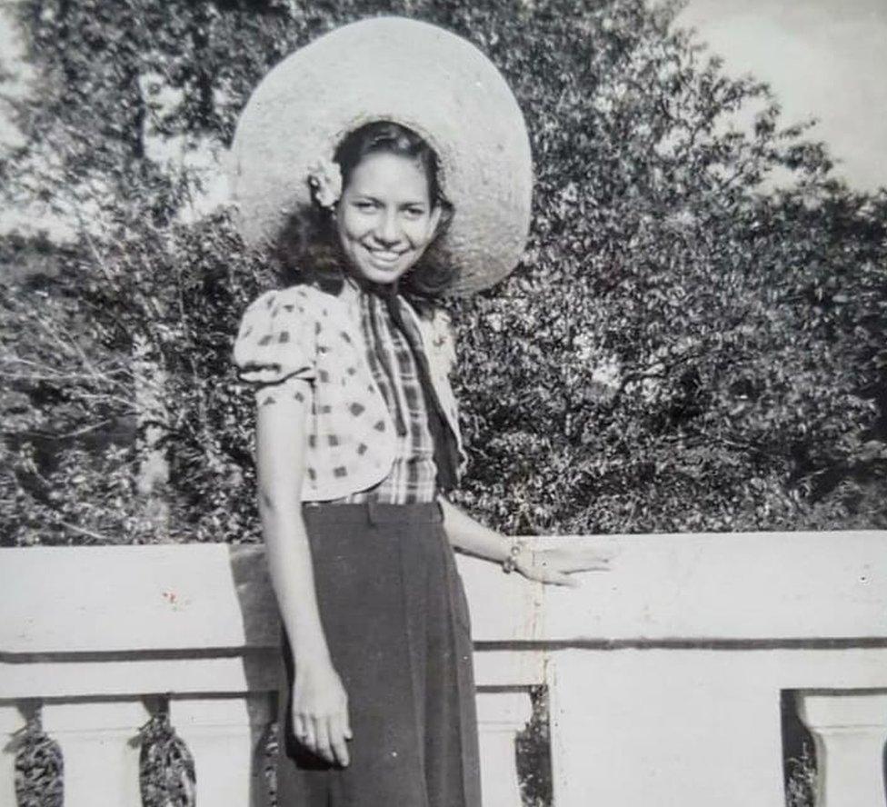 Grace posing with a huge hat in front of a bridge