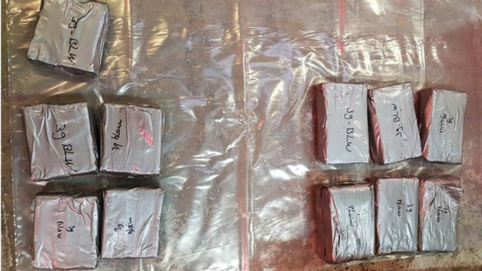 A police evidence photograph showing 11 square parcels containing class A drugs.