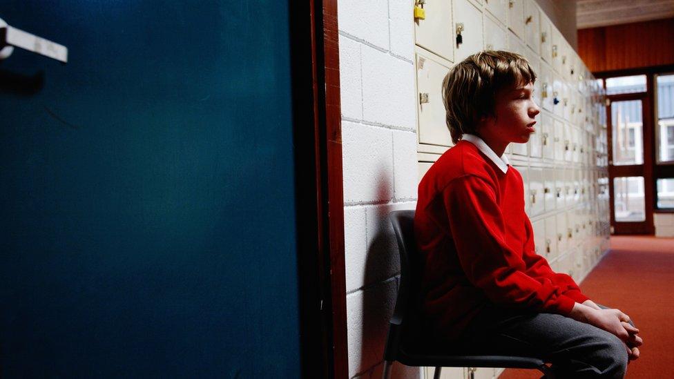 Child seated outside school office