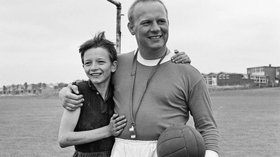 David Bradley, (aged 14) playing the part of Billy Casper, on the film set of the film Kes. Here Billy Casper is playing the goalkeeper in the school football match scene. With him is Mr Sugden, played by Brian Glover.