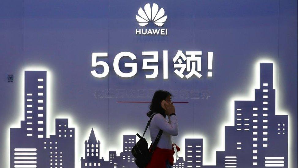 A woman walks past Huawei 5G sign at the PT Expo China 2019 at the China National Convention Center in Beijing, 31 Octobe 2019