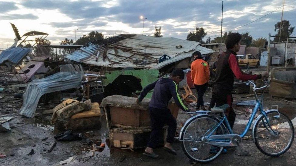 Locals at the scene of a massive car bomb which killed dozens in a used car market in southern Baghdad (16 February 2016)