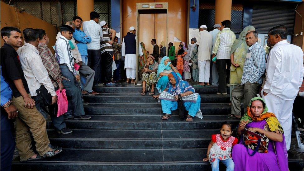 People wait for a bank to open to withdraw and deposit their money, after the scrapping of high denomination 500 and 1,000 Indian rupees currency notes, in Ahmedabad, India, December 5, 2016.