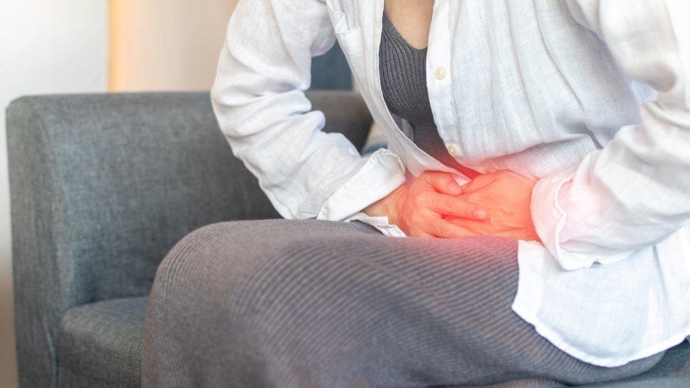 Hands of young woman on stomach as pain or ache from gastrointestinal issues