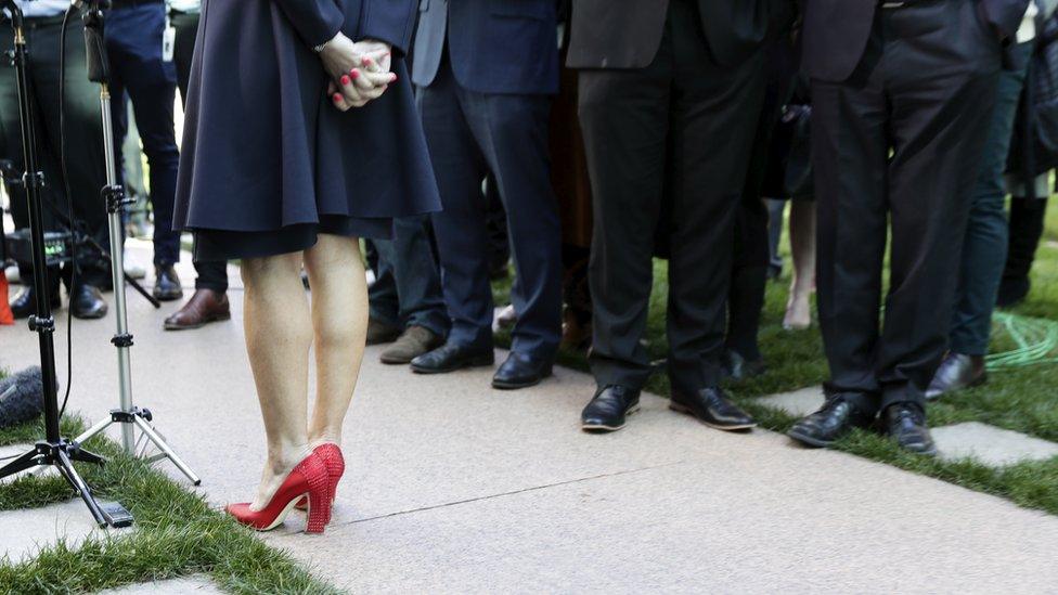 Julie Bishop gives a press conference, with the image framing only her studded red heels against a sea of brogues and dark suits