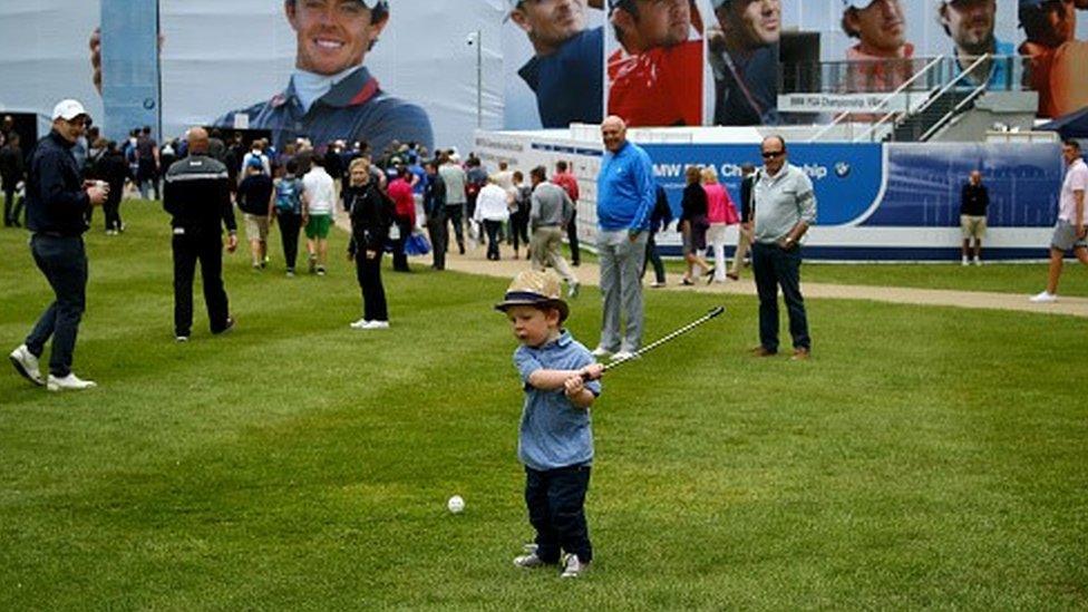 A little boy takes a swing at a golf ball