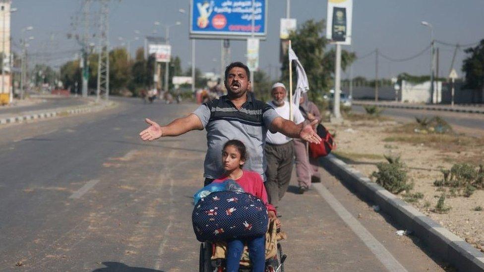 A man walks with his daughter in a wheelchair down Salah al-Din Road