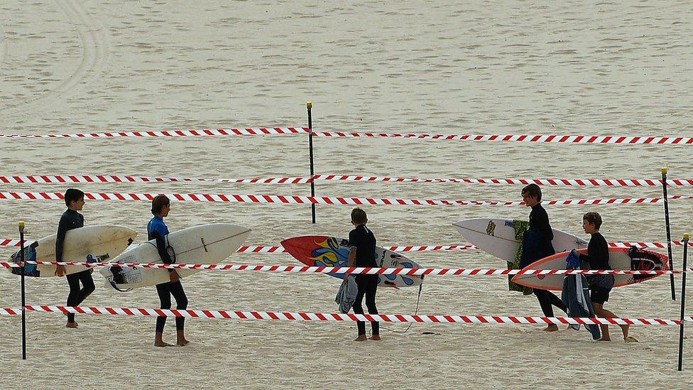 Surfers carry their boards on Bondi Beach after it reopened following a five week closure in Sydney