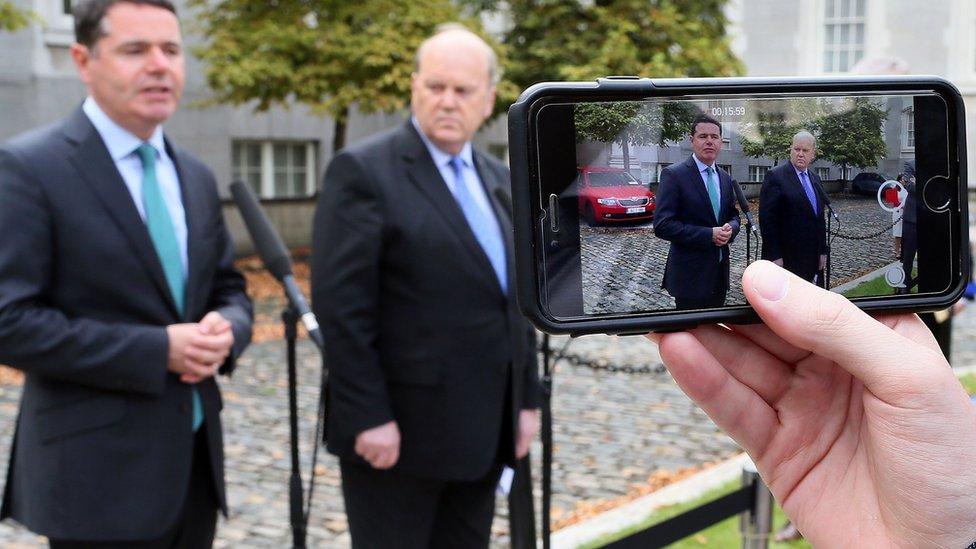 Ministers Michael Noonan (R) and Paschal Donohoe are filmed on an iPhone during a press conference on the Apple Tax ruling, September 2, 2016