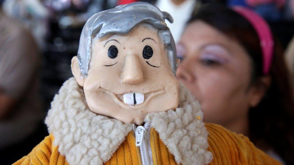 A supporter holds a figure of leftist frontrunner Andres Manuel Lopez Obrador as she takes part in his campaign rally